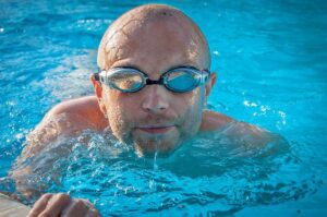 Close-up of a man with swim goggles looking at the camera.